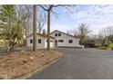 Charming white exterior with red roof, a large driveway, and mature trees surrounding the property at 2469 Cape Henry Ct, Cicero, IN 46034