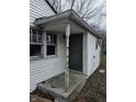 Weathered front entrance with a green door, white siding, and a damaged window at 4210 E Naomi St, Indianapolis, IN 46203