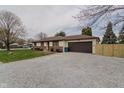Ranch home with a gravel driveway leading to an attached garage, complemented by a tidy front yard at 5510 Chelsea Rd, Indianapolis, IN 46241