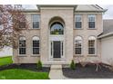Close up of the home's facade featuring the light brick, black front door, and arched window at 559 Hythe Way, Westfield, IN 46074