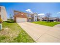 Two-story home with brick facade, attached garage, and long driveway on a sunny day at 5820 Marble Ct, Anderson, IN 46013