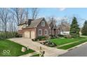 Brick and siding home features a two-car garage, driveway, and manicured lawn at 5861 Dawnwood Dr, Carmel, IN 46033