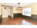 Inviting dining area with modern chandelier, wainscoting, wood floors, and access to stairway at 6479 Enclave Blvd, Greenwood, IN 46143