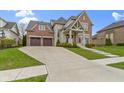 Elegant brick home featuring a two-car garage, manicured lawn, and stone detailing on the front facade at 6590 W Deerfield Dr, Zionsville, IN 46077