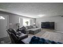 Well-lit living room showcasing plush seating, a TV, and neutral decor at 712 Valley Dr, Anderson, IN 46011