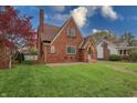 View of a brick home featuring a gabled roof, arched entry, and lush, green landscaping at 720 22Nd St, Columbus, IN 47201