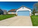 Lovely home with a blue garage door and well-maintained front lawn under a clear blue sky at 7230 Carrie Dr, Indianapolis, IN 46237