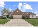 Inviting one-story residence with brick facade, neutral siding, lush lawn and driveway leading to an attached garage at 7441 Sugar Pine Ct, Avon, IN 46123