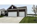 Modern home showcasing a two-car garage with a concrete driveway, and lakeside views at 8755 Stoddard Ln, Indianapolis, IN 46217