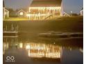 Lakefront home with string lights on the patio and a reflection in the water at night at 8755 Stoddard Ln, Indianapolis, IN 46217
