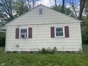 A close-up of a home's exterior showing a window unit, red shutters, and horizontal siding at 1105 N Livingston Ave, Indianapolis, IN 46222