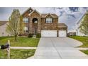 Beautiful two-story brick home with lush green lawn, mature tree, and spacious three-car driveway at 1583 Valdarno Dr, Greenwood, IN 46143