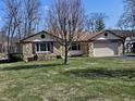Charming ranch-style home with a stone facade, two-car garage, and a tree in front at 1647 S Plateau Cir, Martinsville, IN 46151