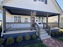 This covered front porch is stylishly appointed with a modern railing, custom welcome sign, and upgraded trim at 2029 Winton Ave, Indianapolis, IN 46224