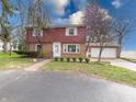 Charming two-story brick home featuring an attached garage and a well-maintained front yard with mature trees at 2215 W State Rd, Pendleton, IN 46064