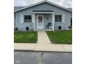 Inviting front porch with a decorative wreath, a chair, potted plants, and a well-manicured lawn at 2715 Prosperity Dr, Columbus, IN 47201