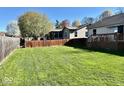 Lush backyard with green grass and wood fence, offering plenty of space at 305 S Schroeder Rd, Muncie, IN 47304