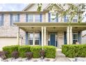 Inviting two-story home featuring a covered front porch, brick facade, blue door and shutters, and manicured landscaping at 3724 Jonathan Rdg, Columbus, IN 47201