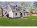 Classic two-story home showcasing light-colored siding, a well-kept lawn, and a detached garage at 402 N 19Th Ave, Beech Grove, IN 46107