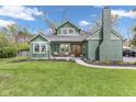 Charming green home with a brick chimney and a manicured lawn, inviting front porch, and beautiful curb appeal at 6185 Evanston Ave, Indianapolis, IN 46220