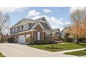Elegant home featuring a three-car garage, brick accents, gray siding, and lush landscaping at 6645 Braemar N Ave, Noblesville, IN 46062
