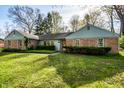 Ranch-style home boasts a lush green lawn and mature trees at 6911 N Tuxedo St, Indianapolis, IN 46220