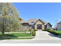 Inviting two-story home with stone facade, manicured front lawn, and blossoming trees at 7128 Trail Ridge Ln, Indianapolis, IN 46259