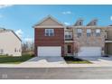 Two-story townhome showcasing an attached garage, brick facade, and well-maintained lawn on a sunny day at 9725 Thorne Cliff Way # 105, Fishers, IN 46037