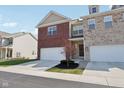 Charming townhome showcasing an attached garage, brick facade, and well-manicured lawn under a bright sunny sky at 9725 Thorne Cliff Way # 105, Fishers, IN 46037