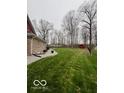 Expansive backyard with mature trees, gravel beds along the house, and a red barn in the distance at 1066 N Dogwood Way, Greenfield, IN 46140