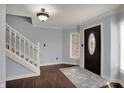 Bright foyer featuring hardwood floors, decorative rug, staircase and a dark wood door flanked by windows at 1444 Trail Creek Ct, Carmel, IN 46032