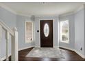 Bright foyer with hardwood floors, decorative rug, and dark wood door flanked by windows allowing natural light at 1444 Trail Creek Ct, Carmel, IN 46032