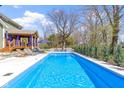 Backyard view of a refreshing in-ground pool with patio seating, landscaping, and wooden pergola at 15385 Ellington Dr, Fishers, IN 46040