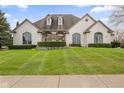 Stunning white brick home with manicured lawn, arched windows and dormers offering timeless appeal at 1583 E Osprey Dr, Greenfield, IN 46140