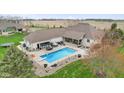 Aerial view of backyard with swimming pool, outdoor kitchen, hot tub, patio, and white brick home at 1583 E Osprey Dr, Greenfield, IN 46140