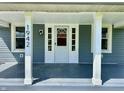 Inviting covered front porch with white columns, updated flooring, and a bright front door at 1942 E Edgewood Ave, Indianapolis, IN 46227
