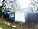 Detached one car garage with white door and blue siding and a privacy fence at 404 W Green St, Lebanon, IN 46052