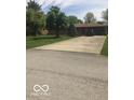 Spacious driveway leading to a single-story brick home with mature trees and a well-maintained lawn at 4329 Dudley N Dr, Indianapolis, IN 46237