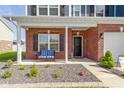Inviting front porch with brick columns, a cozy bench, and lush landscaping creating a warm and welcoming entrance at 4638 W Otway Ln, New Palestine, IN 46163