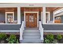 The beautiful front porch features a stained wood ceiling, front door, and manicured landscape at 5619 Carrollton Ave, Indianapolis, IN 46220