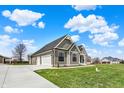 View of the house featuring a three-car garage, complemented by lush green grass and blue sky at 706 E 750 N, Lebanon, IN 46052
