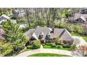 Aerial view of a brick home with a circular driveway and beautiful landscaping at 7545 Chablis Cir, Indianapolis, IN 46278