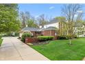 Side view of home with brick and white siding, attached garage, and landscaped yard at 8027 Heyward Dr, Indianapolis, IN 46250