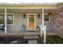 A covered front porch with stylish decor, including wall lanterns, plants, and a welcome wreath at 1109 Oakwood Trl, Indianapolis, IN 46260