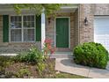 Inviting front entrance with a green door, brick accents, and well-maintained garden bed at 12326 River Valley Dr, Fishers, IN 46037