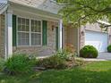 Close-up of the front yard with a brick facade, green shutters, and vibrant landscaping at 12326 River Valley Dr, Fishers, IN 46037