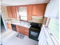 Well-lit kitchen with wood cabinets, black appliances, and a window with a garden view at 126 Mercator Dr, Greenwood, IN 46143
