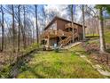 Backyard with stairs leading to a deck, chairs, fire pit, and surrounding trees at 13306 W 50 S, Columbus, IN 47201