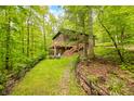 View of a cozy backyard with a fire pit and stone pathway leading to a wooden house in the woods at 13306 W 50 S, Columbus, IN 47201