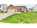 Inviting single-story home with a brick facade, attached garage, well-maintained lawn, and a red front door at 1632 Blankenship Dr, Indianapolis, IN 46217